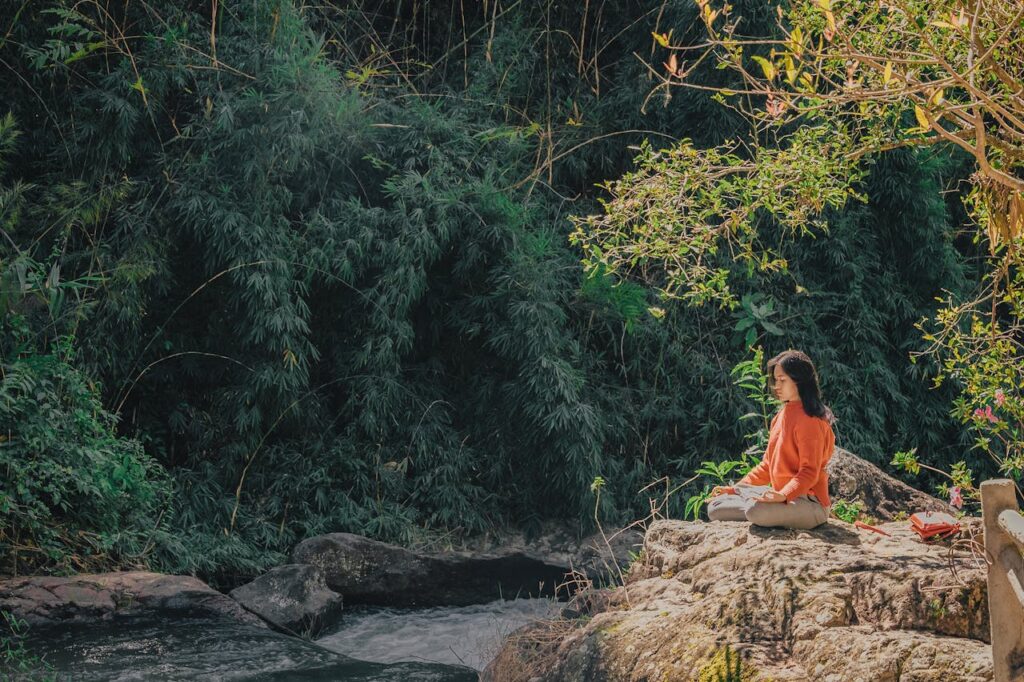 Benefícios da Meditação Guiada para Ansiedade e Estresse - Foto de Min An: https://www.pexels.com/pt-br/foto/mulher-sentada-em-pedra-marrom-perto-de-arvores-de-folhas-verdes-durante-o-dia-1234035/